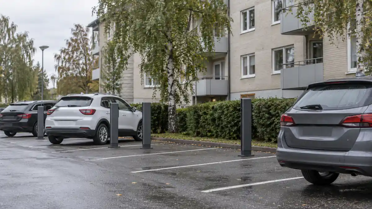 Parkering vid ett svenskt bostadsrättshus med laddstolpar mellan rutorna en mulen dag